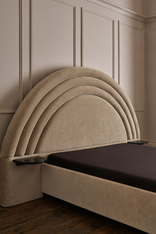 The Curve Bed Whisper styled with a dark sheet on a mattress, displayed in front of a neutral panelled wall.