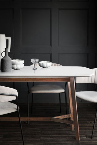 The Curved Acacia & Marble Dining Table styled with dining accessories on, with some grey dining chairs.