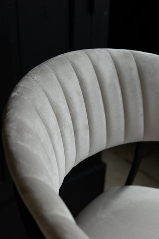 Close-up image of the back rest on the Curved Back Velvet Dining Chair In Mink Grey in a dark room