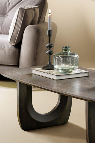 Close-up of the Curved Mango Wood Coffee Table styled with a book, vase and lit candle in a candlestick holder on the top.