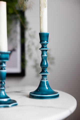 Detail shot of the Tall Deep Blue Enamel Cast Style Candlestick Holder on a white table.