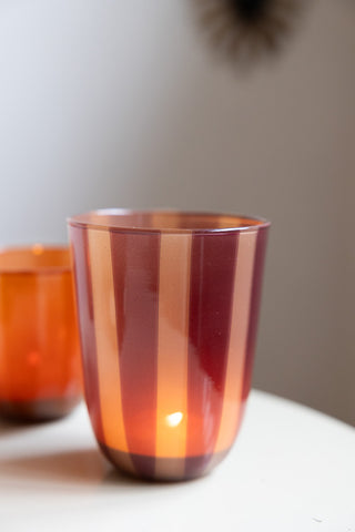 Close-up of the Deep Bordeaux Striped Tealight Holder - Tall with a lit tealight inside, with another smaller tealight holder in the background.