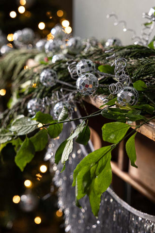 The Disco Ball Clip on Christmas Decoration styled on a wooden disco fireplace on a greenery garland.