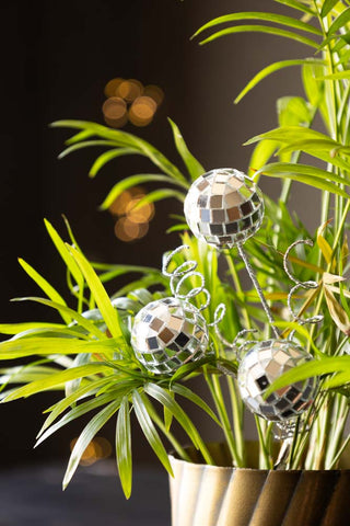 The Disco Ball Clip on Christmas Decoration styled amongst a plant in a plant pot.