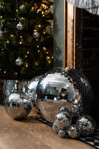 The Silver Disco Ball - 40cm in front of a christmas tree styled with other disco decorations.