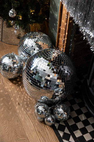 The Silver Disco Ball - 40cm shown from above on a checkered floor in front of a fireplace.