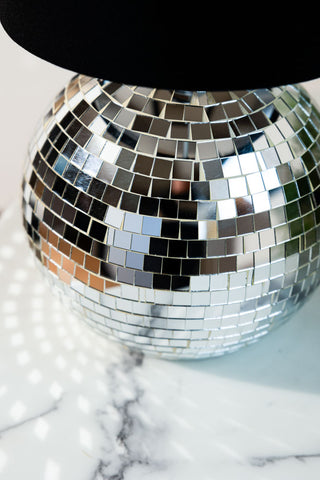 Close-up of the Disco Ball Table Lamp in Silver displayed on a white marble table.