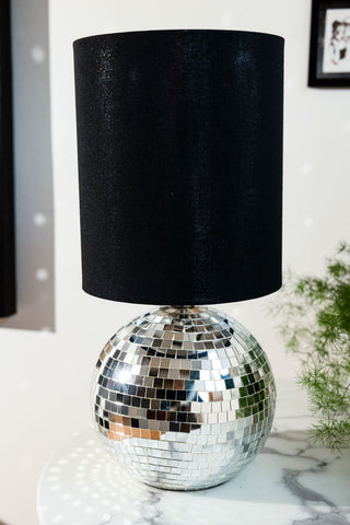 The Disco Ball Table Lamp in Silver styled on a marble table with a plant.