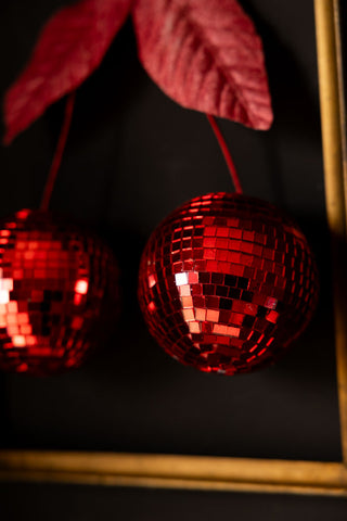 Detail shot of the Disco Cherries Christmas Tree Decoration hanging on a dark wall inside a frame.