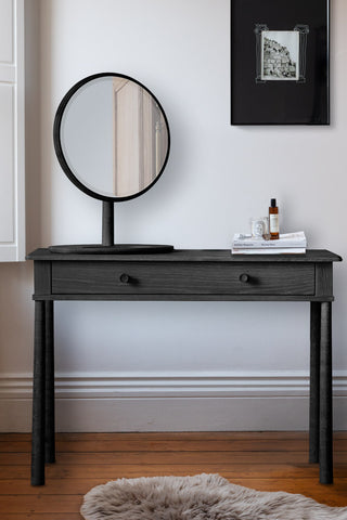 The Elegant Black Dressing Table styled in front of a white wall, with various accessories.