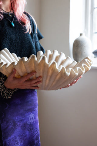 A large decorative shell bowl being held in a model's hands.