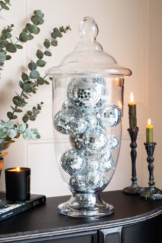 Clear glass apothecary jar with a domed lid, perfect for decorative or functional use, styled with candles and foliage.