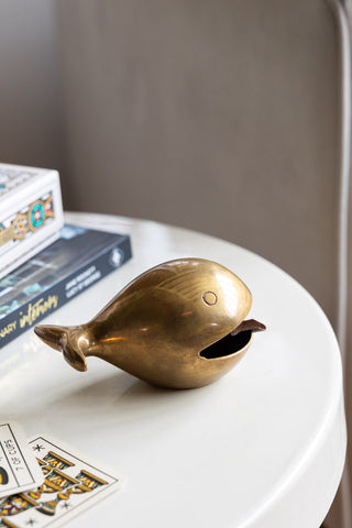 The Fabulous Antique Gold Whale Ornament/Ashtray styled on a table with other books and some illustrated cards.