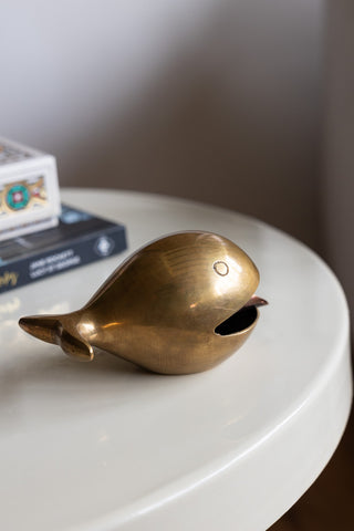 The Fabulous Antique Gold Whale Ornament/Ashtray displayed on a table with some books.