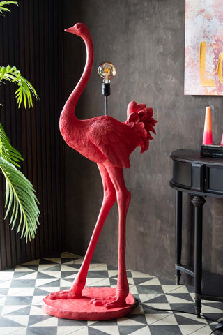 The Fabulous Pink Ostrich Floor Lamp styled with a plant, table, candles, books and canvas.