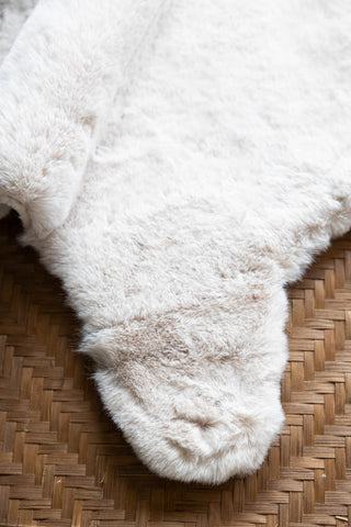 Detail shot of the Faux Fur Natural Rug on a wicker bench, seen from above.