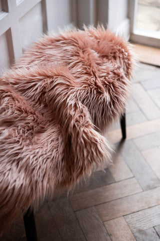 The Faux Sheepskin in Blush draped across a bench.