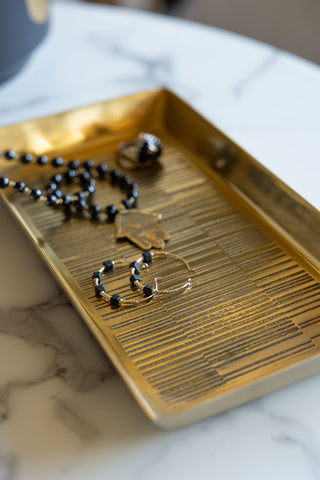 Close-up of the Fine Line Detail Gold Effect Trinket Tray seen from above, styled with some jewellery inside.