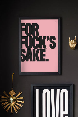 The For Fuck's Sake Pink & Black Art Print - Unframed displayed in a black frame on a black wall, styled with another art print and some gold wall ornaments.