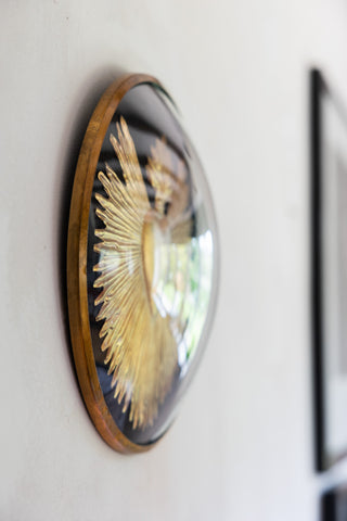 Side view of the Framed Golden Milagro Heart Decoration on a white wall, next to some framed art prints.