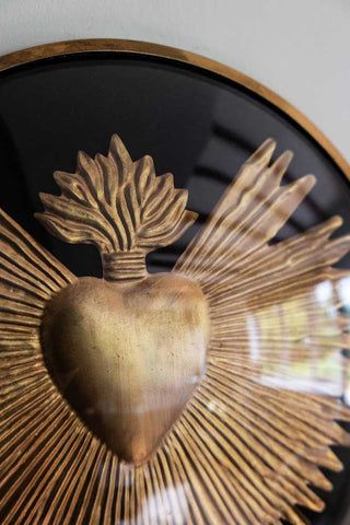 Close-up of the Framed Golden Milagro Heart Decoration on a white wall.