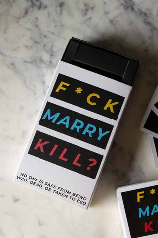 The box of the Fuck, Marry, Kill Card Game displayed on a white marble surface, with cards at the corner.