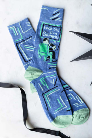 The Fuck Off, I'm Gaming Mens Socks displayed on a white surface with some ribbon and a star decoration.