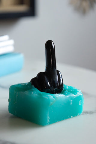 Close-up of the Fuck You Candle with outside layer burnt to reveal the hidden inside, displayed on a white marble table.