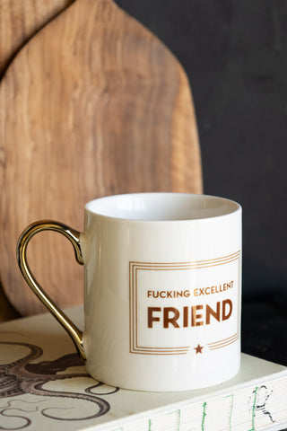 A white mug with a sweary statement and a gold handle 