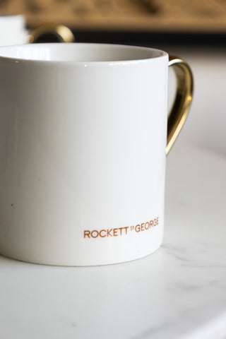 The back of a white ceramic mug with the Rockett St George logo on it