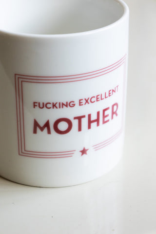 A close up of the words 'F*cking Excellent Mother' on a white ceramic mug 