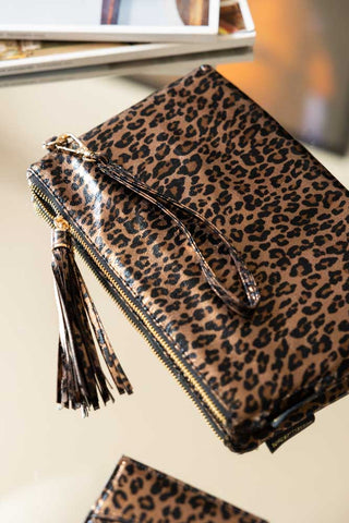 The Glam Leopard Print Clutch Bag displayed on a table with some magazines and the matching card holder.