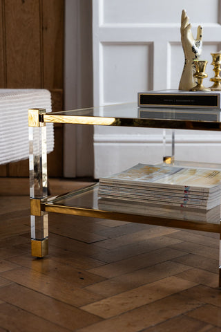 Close-up of the Gold & Glass Coffee Table seen from the side, styled with magazines and home accessories on.