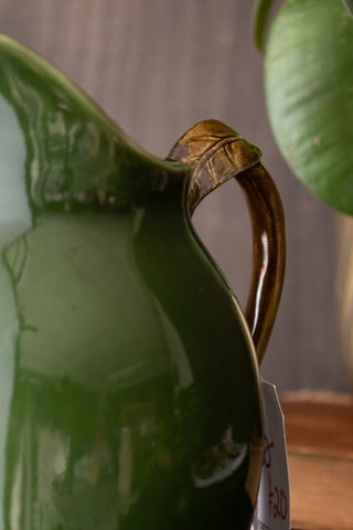 Close-up of the brown leaf handle of the green jug.