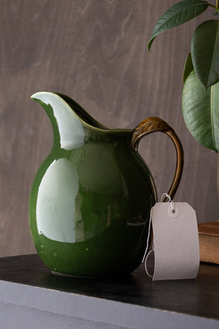 Green glazed jug with slight dents and imperfections. There are slight colour issues.