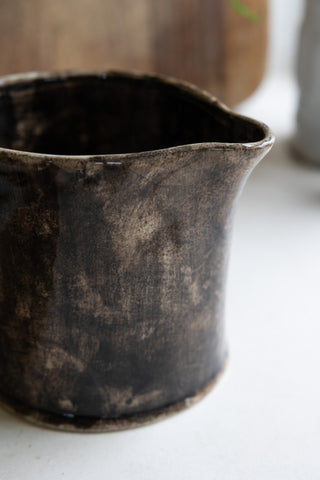 A close-up of a black and brown mottled-effect ceramic jug 