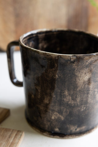 A close-up of the handle of a brown ceramic jug