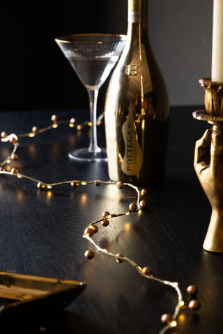 A gold berry fairy light snaking down the centre of a table.