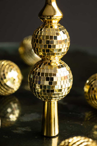 Close-up of the base of a Gold Disco Ball Christmas Tree Topper, with multiple matching baubles in the background of the shot.