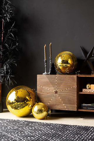 The Gold Disco Ball - 20cm styled with two other sizes on/around a wooden unit with various home accessories on.