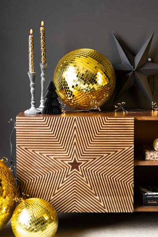 The Gold Disco Ball - 30cm styled on a wooden unit with Christmas decorations and candles.