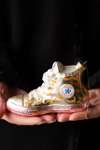 The Gold Glass Sneaker Christmas Tree Decoration being held in a model's hands.