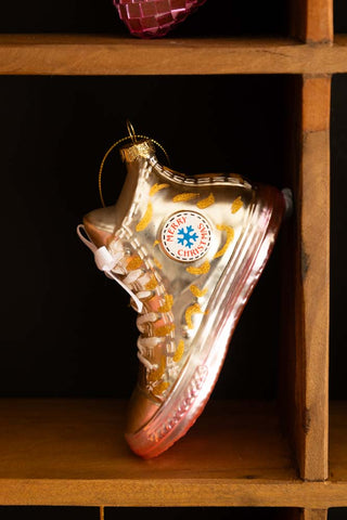 The Gold Glass Sneaker Christmas Tree Decoration displayed on a wooden shelf.