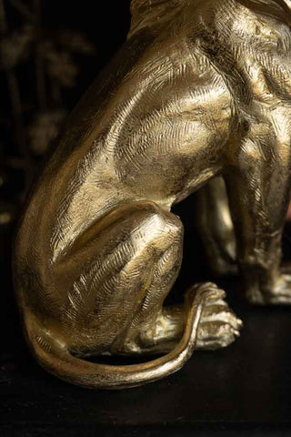 Close-up of the Quirky Gold Lion Lamp on a black surface.