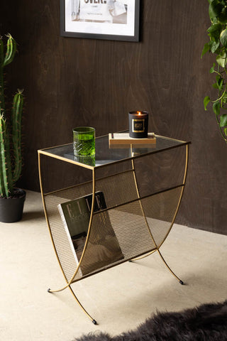 Gold Magazine Rack With Glass Top styled with candle and glass on top with magazine in rack and cactus plant and sheepskin on floor