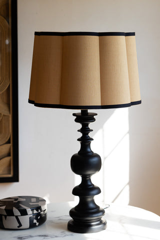 The Gold Scalloped Easyfit Lampshade styled on a lamp base on a white marble table, next to a trinket box and a piece of artwork.