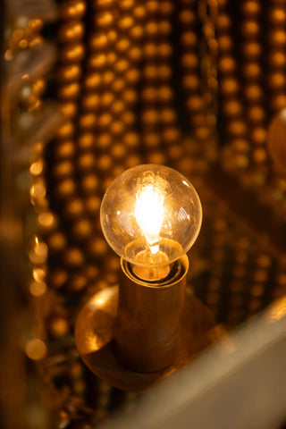 The inside of the Gold Star Shaped Beaded Statement Chandelier Light with a lit bulb.