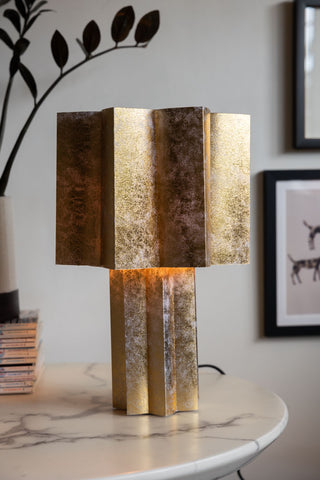 Gold leaf-effect star-shaped table lamp styled on white marble table 