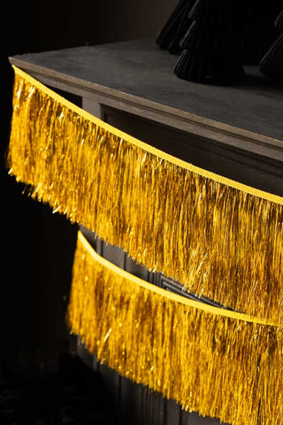 Close-up of the Gold Tinsel Garland styled on the edge of a fireplace.