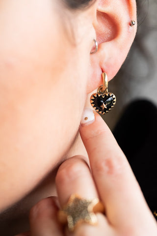 Close-up of the Gold & Black Heart Huggie Hoop Earrings being worn by a model.